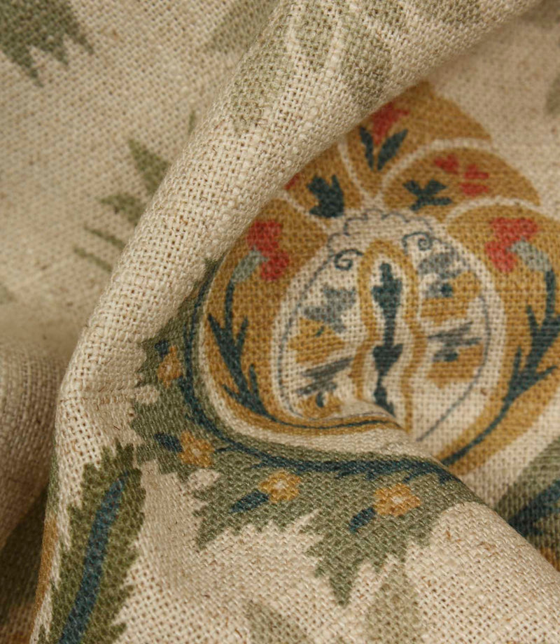 Detailed close-up of textured woven fabric featuring intricate floral medallion design in sage green, ochre and muted red colours.