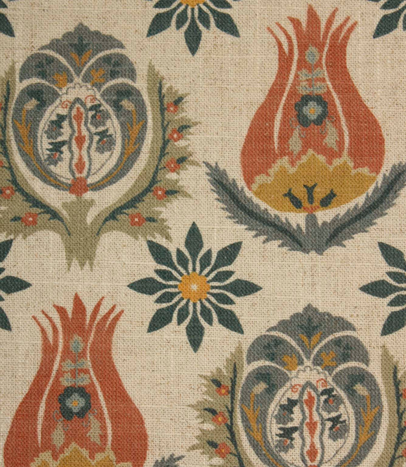 Close-up of decorative botanical fabric featuring stylised tulip motifs and floral medallions in rust red, slate blue and mustard shades.