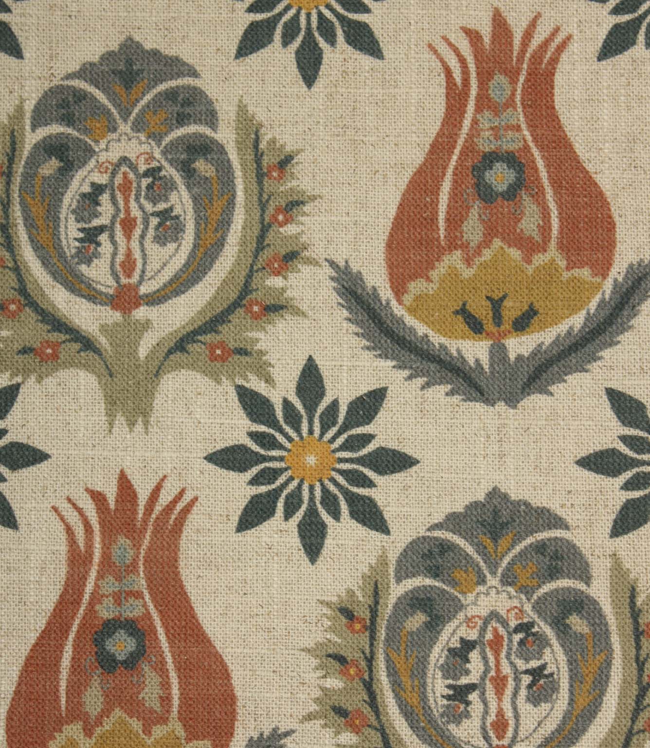 Close-up of decorative botanical fabric featuring stylised tulip motifs and floral medallions in rust red, slate blue and mustard shades.