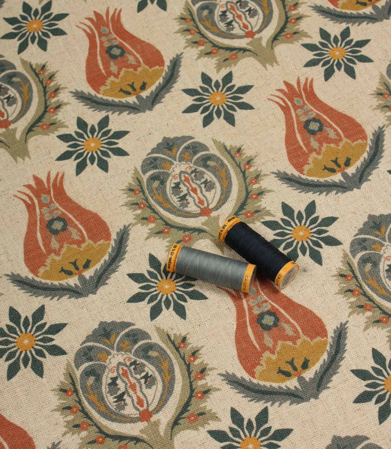 Patterned linen-style fabric displayed with coordinating blue and grey thread reels.