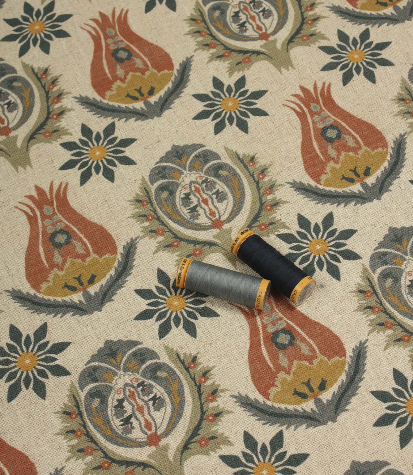 Patterned linen-style fabric displayed with coordinating blue and grey thread reels.