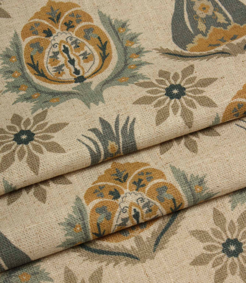 Folded woven fabric with repeating floral medallion pattern in muted blue, ochre and taupe tones.