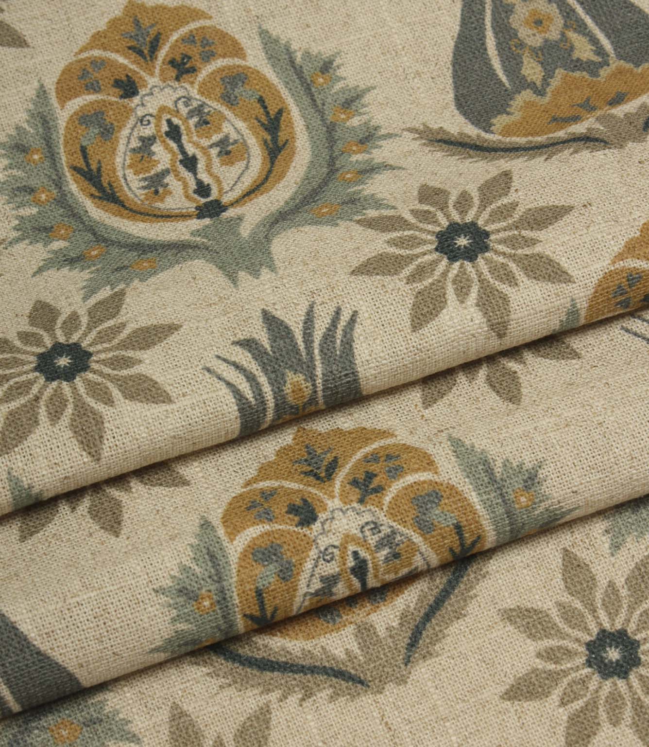 Folded woven fabric with repeating floral medallion pattern in muted blue, ochre and taupe tones.