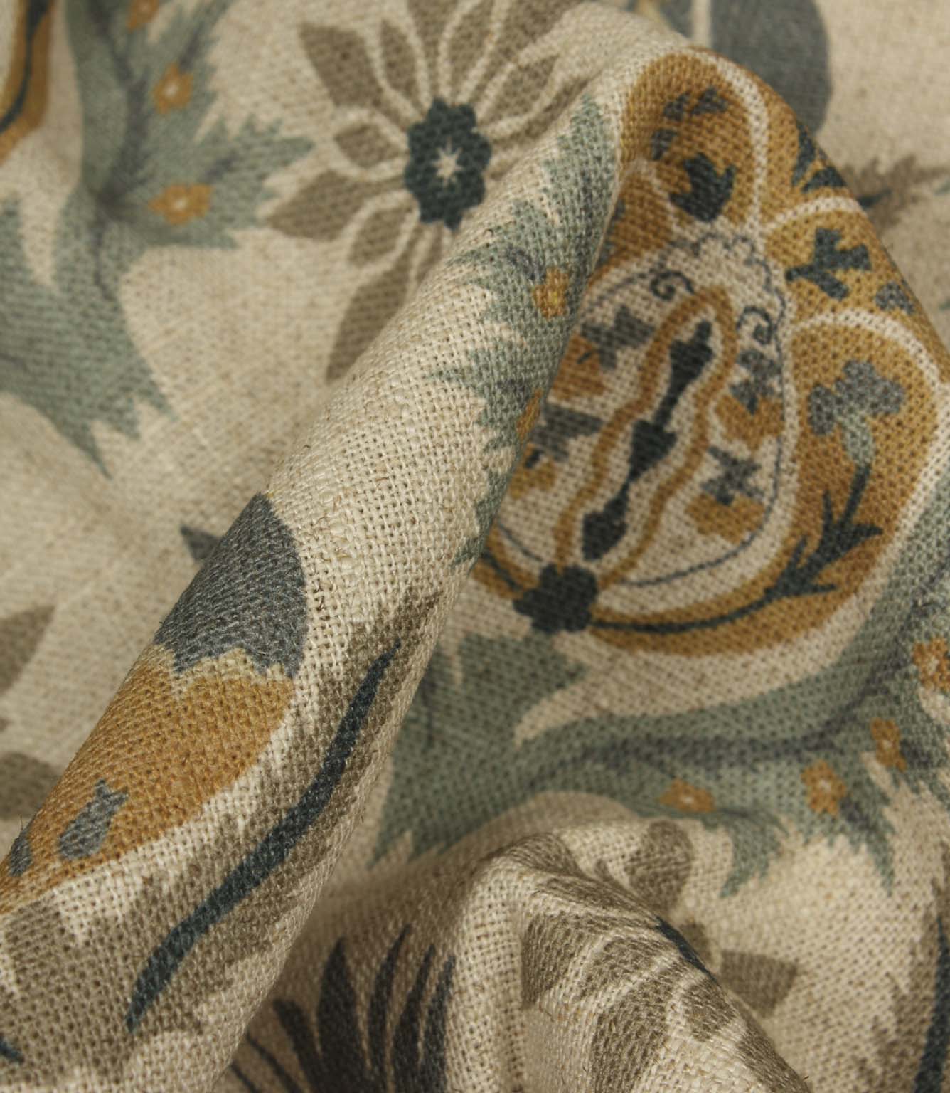 Detailed close-up of textured woven fabric highlighting ornamental floral design in muted blue and ochre tones.