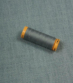 Trento woven plain fabric in sky with coordinating thread spool, demonstrating the fabric's texture, weave and colour match.