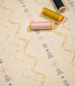 Twilight Mill Gold fabric displayed with coordinating gold, blush and navy sewing thread, highlighting the contemporary geometric print.
