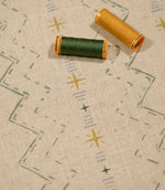 Twilight Mill Green Apple Gold fabric displayed with coordinating green and gold sewing thread, highlighting the contemporary geometric print.