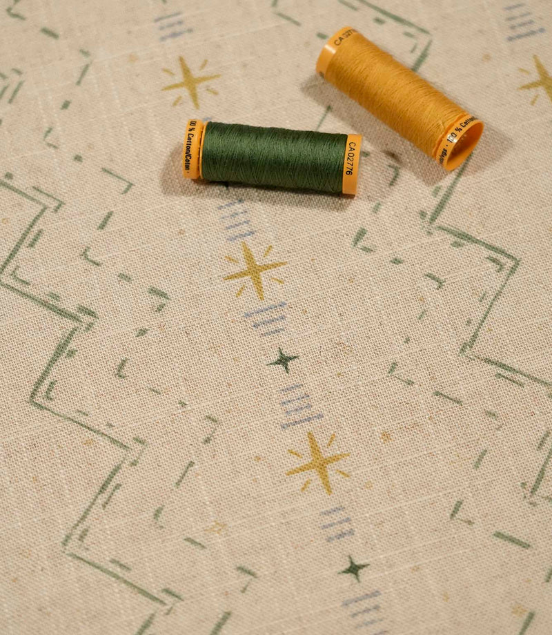 Twilight Mill Green Apple Gold fabric displayed with coordinating green and gold sewing thread, highlighting the contemporary geometric print.