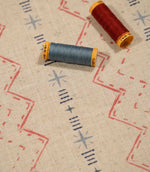 Twilight Mill Red Steel Blue fabric displayed with coordinating red and steel blue thread reels, highlighting the contemporary geometric design.