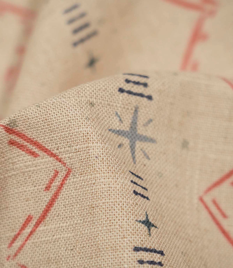 Macro close-up of Twilight Mill Red Steel Blue fabric highlighting the woven texture and hand-drawn geometric motif in red and steel blue.