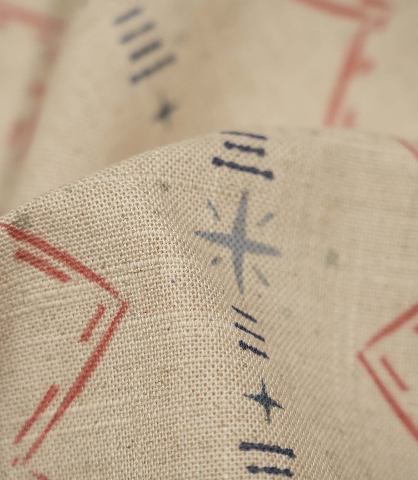 Macro close-up of Twilight Mill Red Steel Blue fabric highlighting the woven texture and hand-drawn geometric motif in red and steel blue.