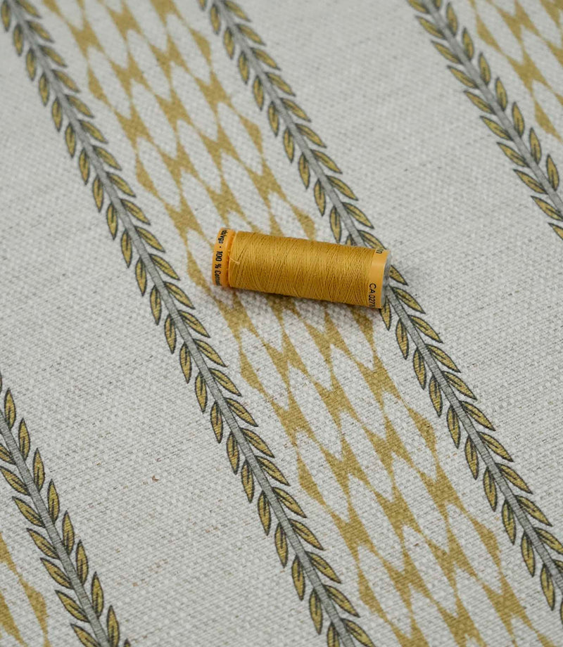 Varese Gold contemporary upholstery fabric with matching thread spool highlighting the fabric texture and pattern scale.