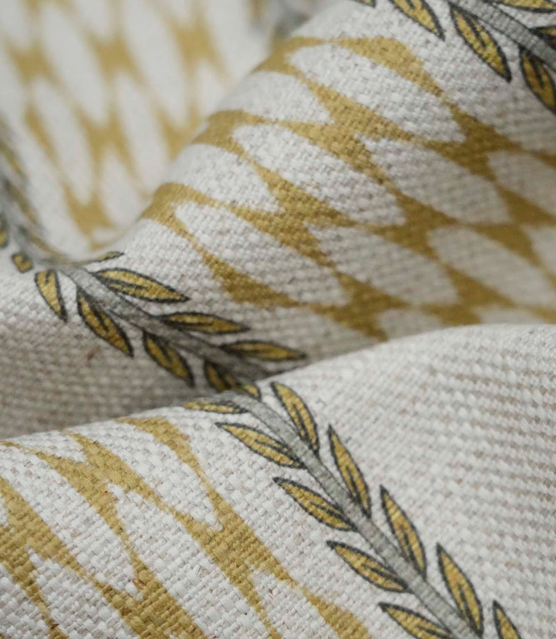 Close-up detail of Varese Gold upholstery fabric showing the woven texture and stylised foliage border.