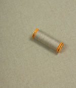 Spool of thread on a textured beige background