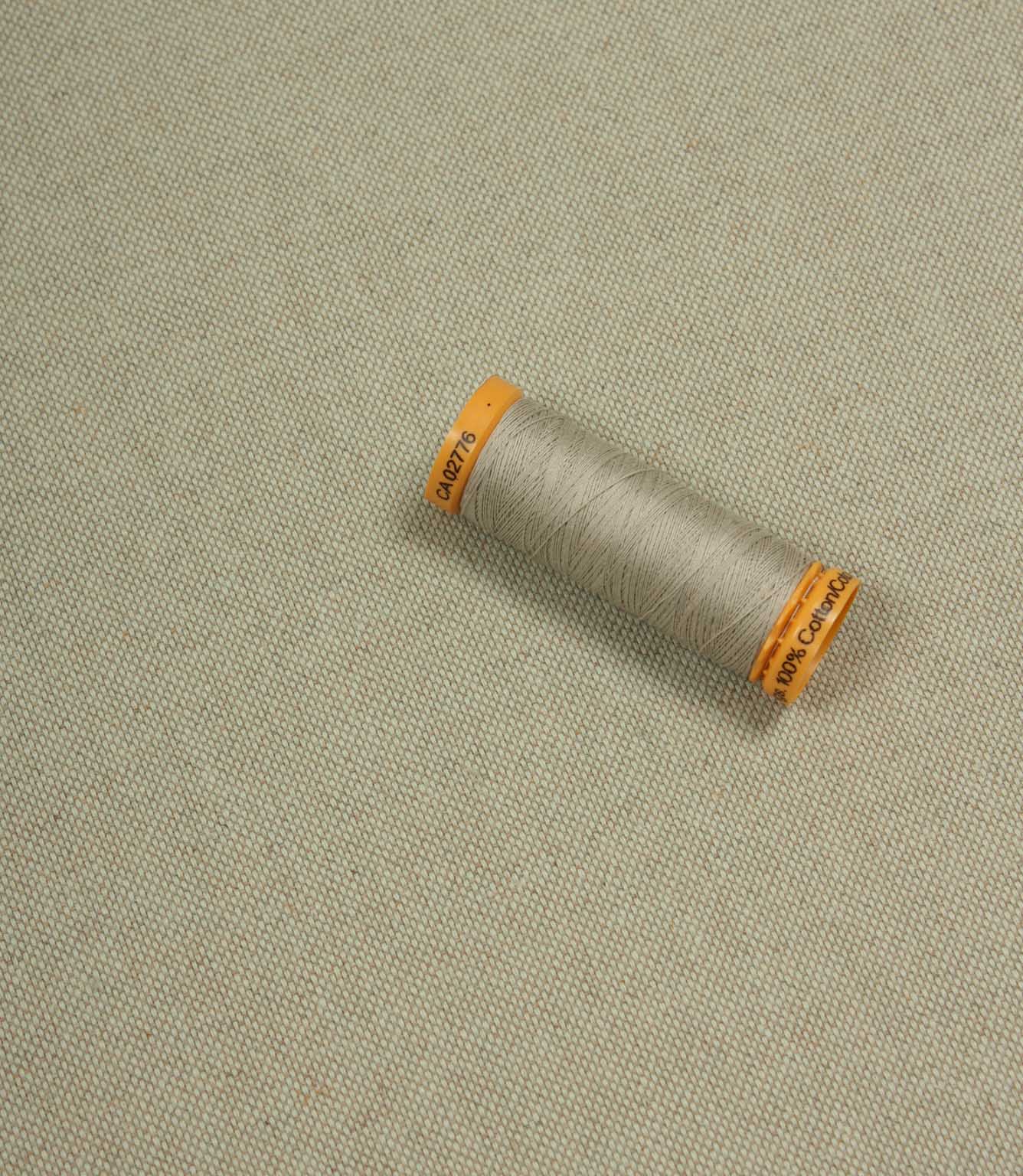 Spool of thread on a textured beige background