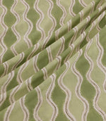 Wading Kelp fabric arranged in soft diagonal folds, showcasing its contemporary wave-inspired stripe design in sage and olive green, with cream scalloped detailing and fine taupe outlines highlighting the fabric's texture and drape.
