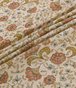 Wainscott Coralee floral curtain and upholstery fabric arranged in soft diagonal folds, showcasing its traditional botanical design of coral orange flowers, turquoise blue accents, golden ochre foliage and delicate trailing stems on a warm ivory background, with a subtly textured woven appearance.