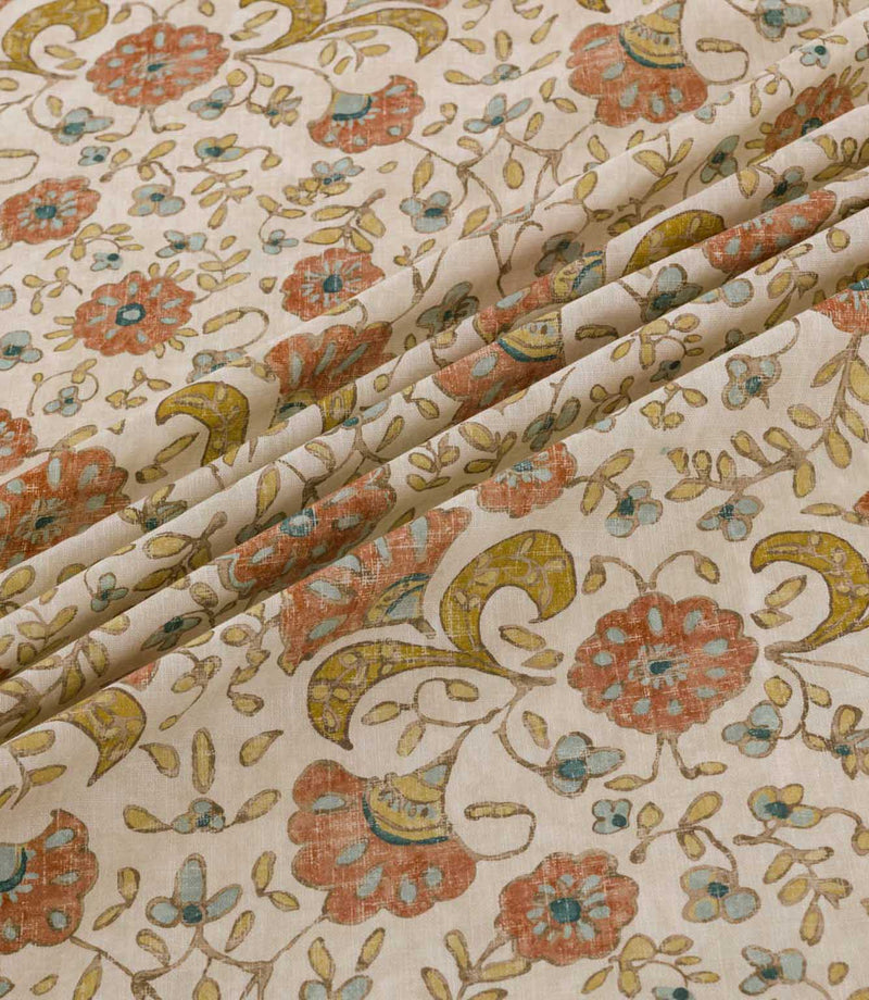 Wainscott Coralee floral curtain and upholstery fabric arranged in soft diagonal folds, showcasing its traditional botanical design of coral orange flowers, turquoise blue accents, golden ochre foliage and delicate trailing stems on a warm ivory background, with a subtly textured woven appearance.