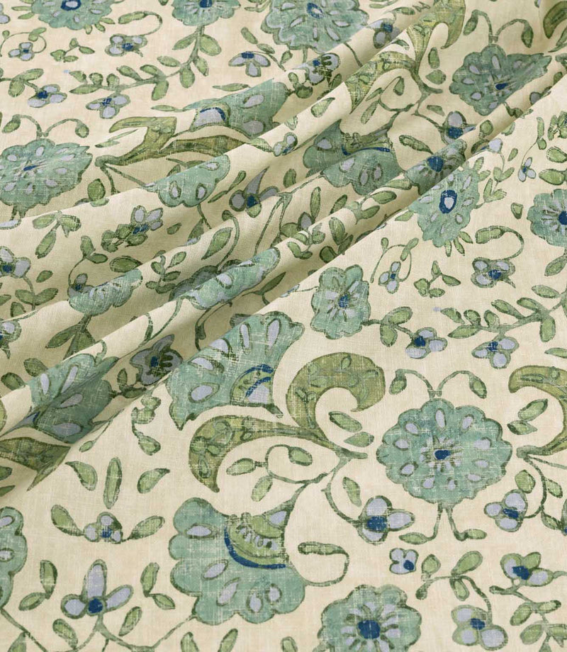 Wainscott Saltwater floral curtain and upholstery fabric arranged in soft diagonal folds, showcasing its traditional botanical pattern of sage green and aqua blue flowers, deep blue accents, scrolling olive green foliage and delicate floral sprigs on a warm ivory background, with a visible woven texture and natural drape.