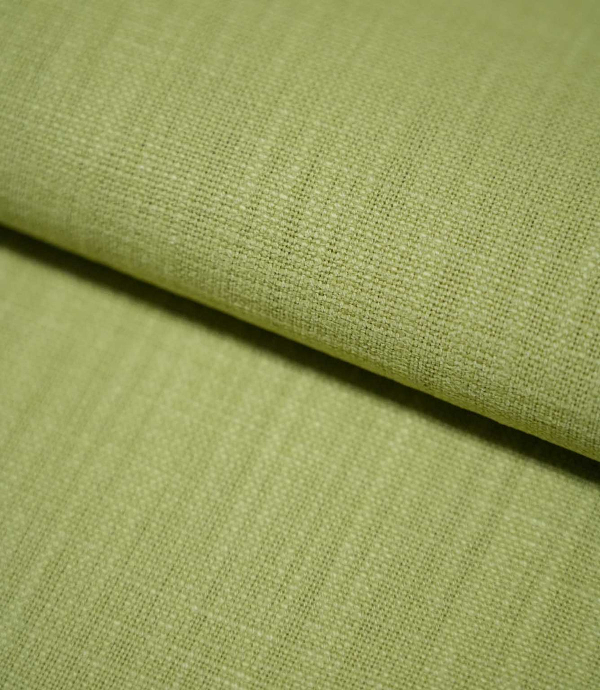 Close-up of Waverley Celery fabric gently folded, revealing its fine basket-like weave, textured surface and muted green colour.