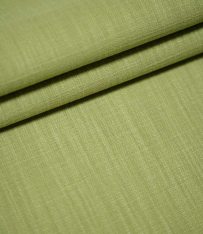 Waverley Celery green upholstery-style fabric arranged in overlapping folds, highlighting its woven texture and subtle tonal variations.