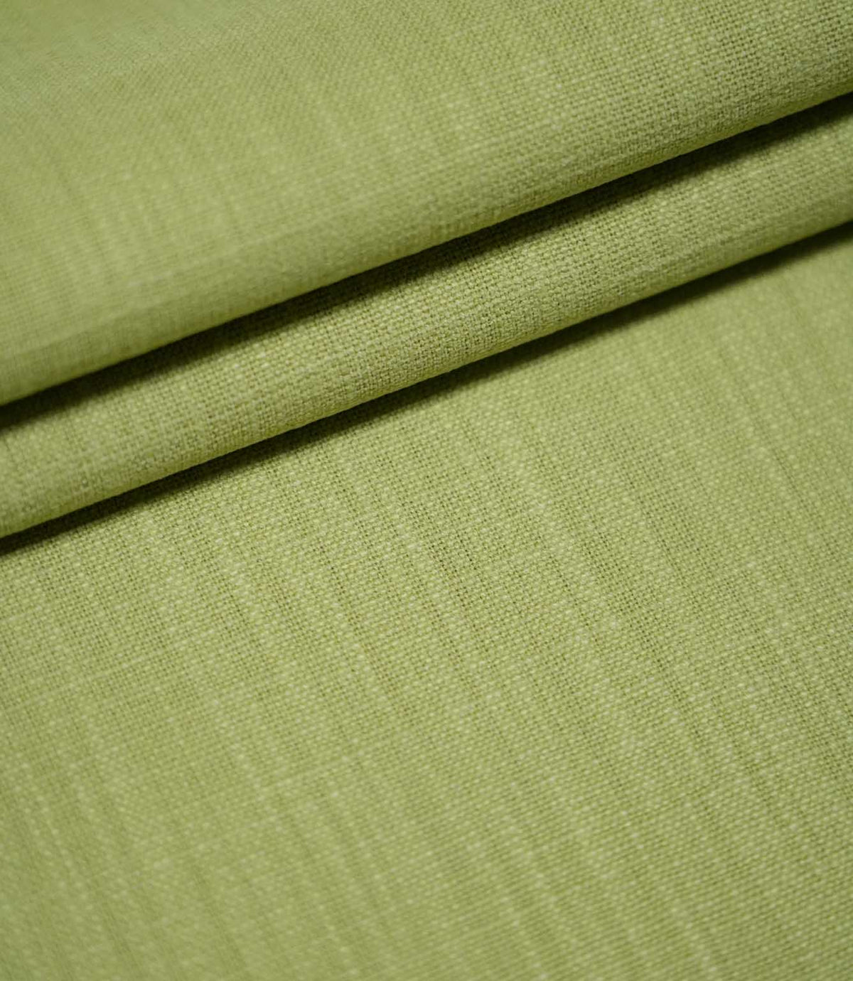 Waverley Celery green upholstery-style fabric arranged in overlapping folds, highlighting its woven texture and subtle tonal variations.