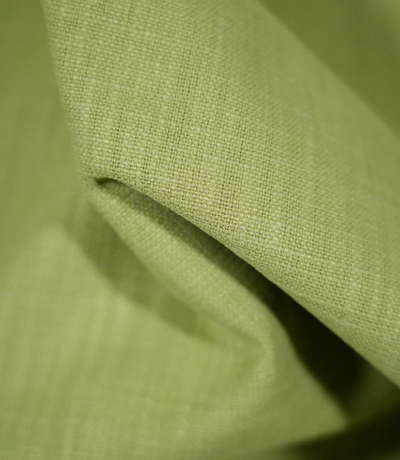 Macro photograph of Waverley Celery fabric draped into a soft fold, showing the detailed green woven threads and textured finish.