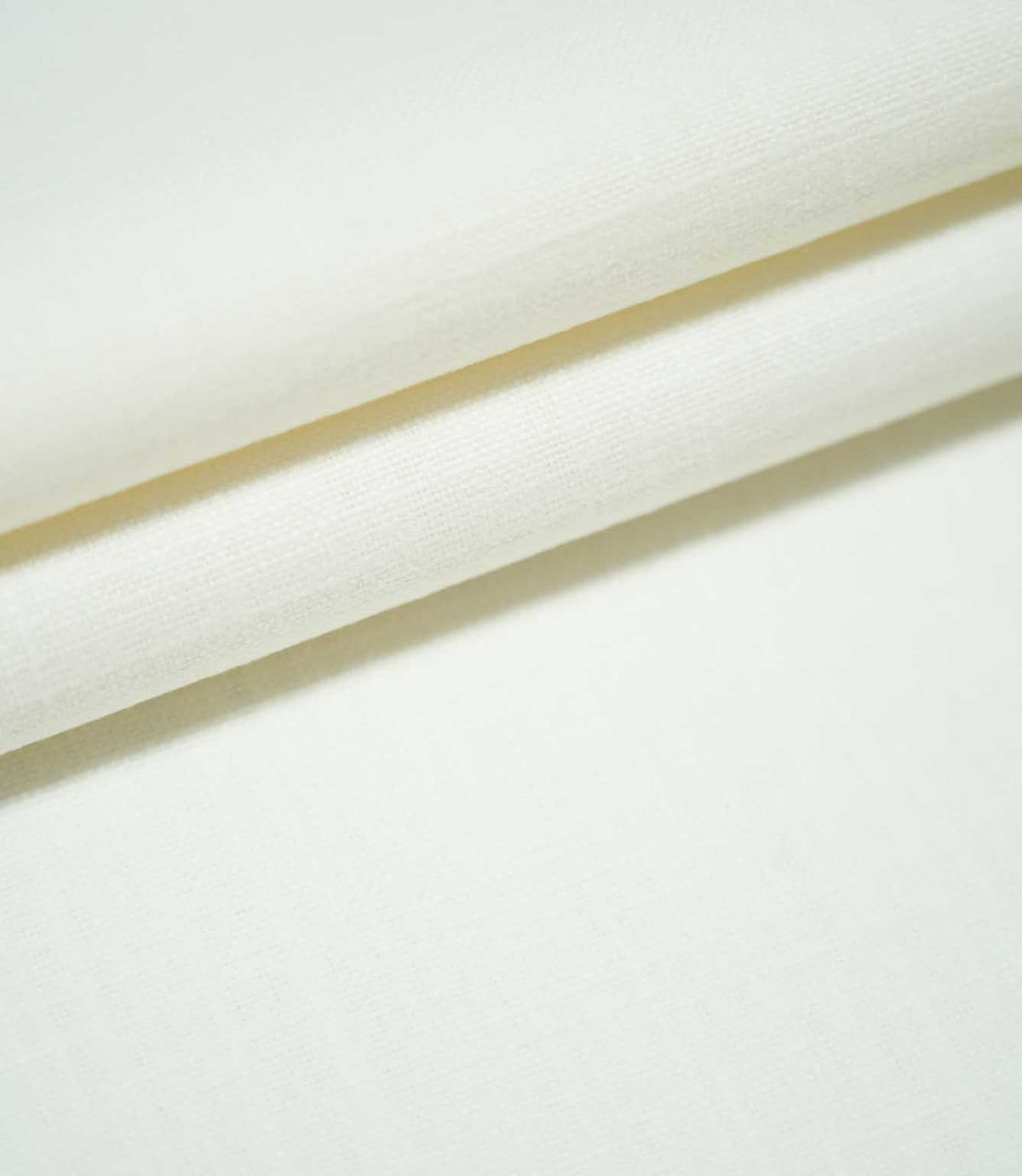 Waverley Chalk plain off-white fabric arranged in overlapping folds, showcasing its fine woven texture and soft, neutral appearance.
