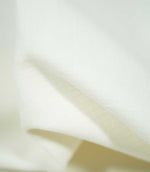 Macro view of Waverley Chalk fabric draped into a gentle fold, highlighting the delicate off-white woven threads and subtle surface texture.