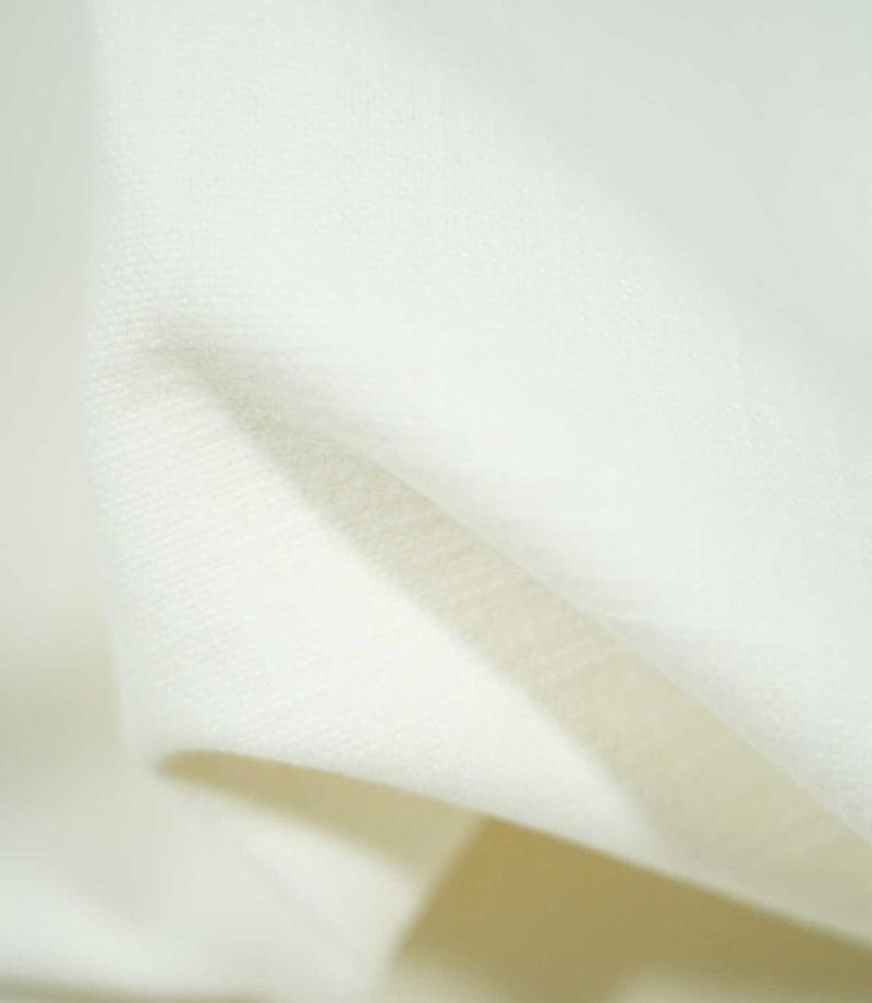 Macro view of Waverley Chalk fabric draped into a gentle fold, highlighting the delicate off-white woven threads and subtle surface texture.