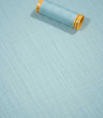 Waverley Duck Egg 100% brushed cotton fabric laid flat with a coordinating pale blue thread spool, highlighting its fine weave and soft blue-green colouring.