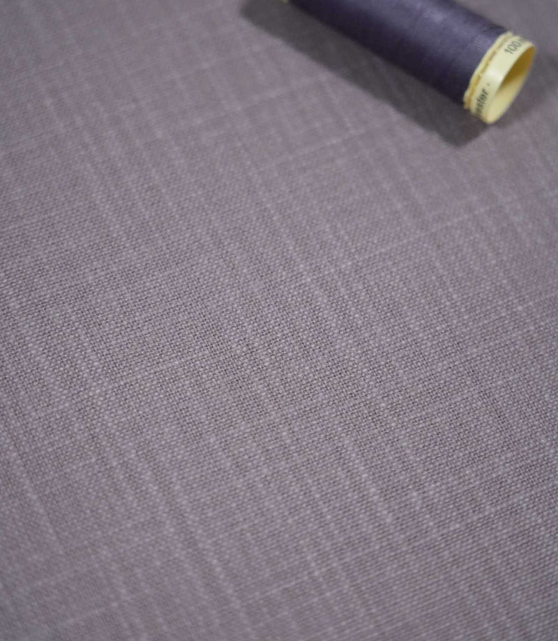 Waverley Heather brushed cotton fabric laid flat with a coordinating deep purple thread spool, highlighting its woven texture and muted lavender-grey colouring.