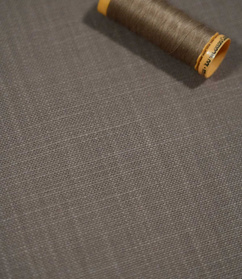 Close-up of Waverley Mink brushed cotton fabric with a coordinating taupe thread spool, highlighting the fine woven texture and warm grey-brown colouring.