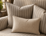 Close-up of striped woven upholstery fabric on cushions and armchair seating, highlighting the soft texture and tailored piping detail.