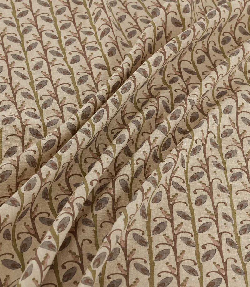 Wildwood Alder fabric draped in soft folds, showing the repeating small-scale botanical pattern of plum leaves, olive green stems and delicate branches on a natural cream ground.