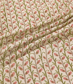Wildwood Rosehip fabric draped in soft folds, showing the repeating small-scale botanical pattern of pink leaves, olive green sprigs and taupe stems on a natural cream ground.