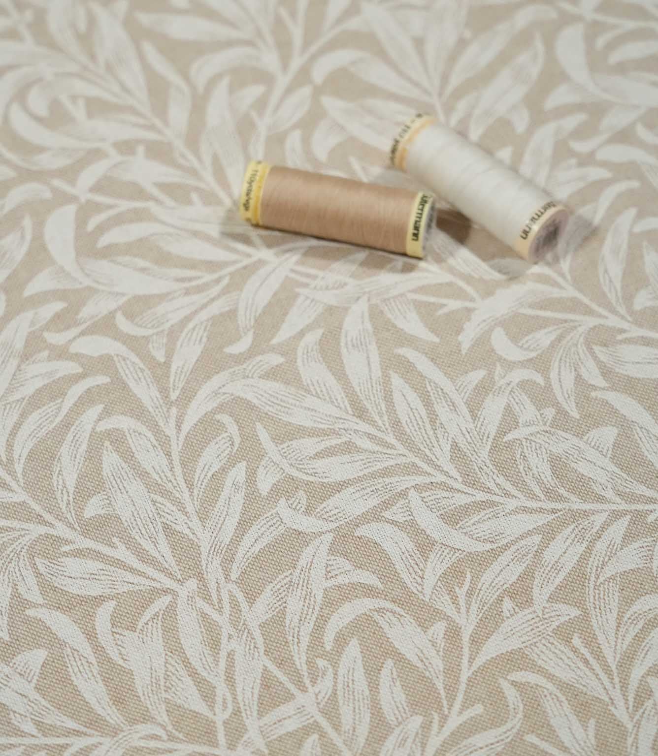 Beige and cream Willow Bough Linen Look fabric with sewing threads, showing the William Morris inspired trailing foliage design and woven texture.