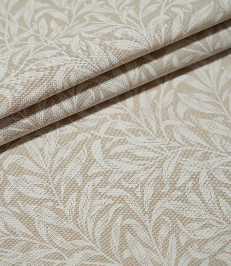 Willow Bough Linen Look fabric arranged in soft folds, showing the cream foliage design against a warm beige ground and the fabric's natural drape.