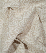 Beige fabric with a white botanical leaf pattern, shown in soft folds.