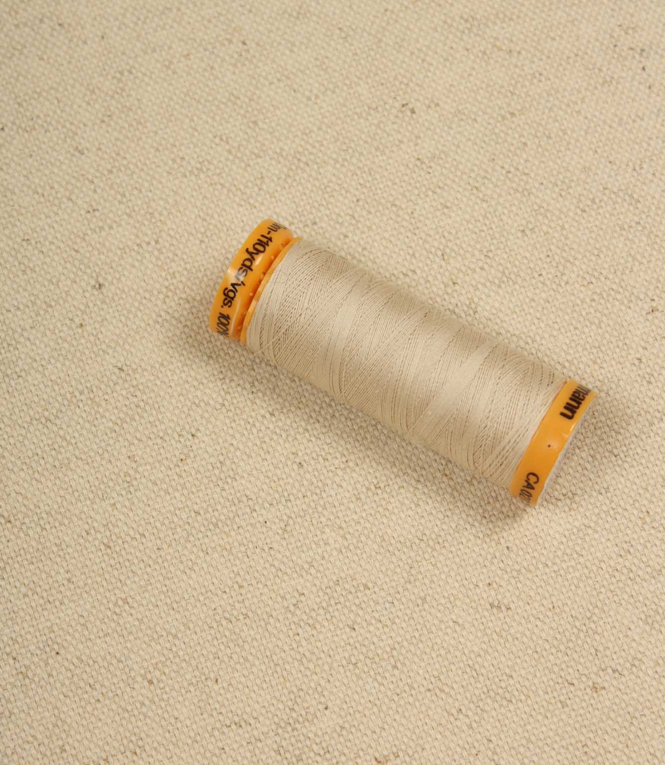 Natural plain woven fabric with spool of thread