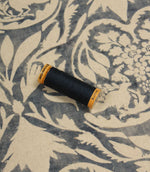 Spool of thread on a blue fabric with floral pattern
