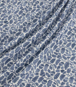 Woodcliff Nautica fabric arranged in soft, flowing folds, showcasing its repeating oak leaf and acorn design in navy and dusty blue tones on an ivory background, with a finely woven texture and delicate foliage detailing.