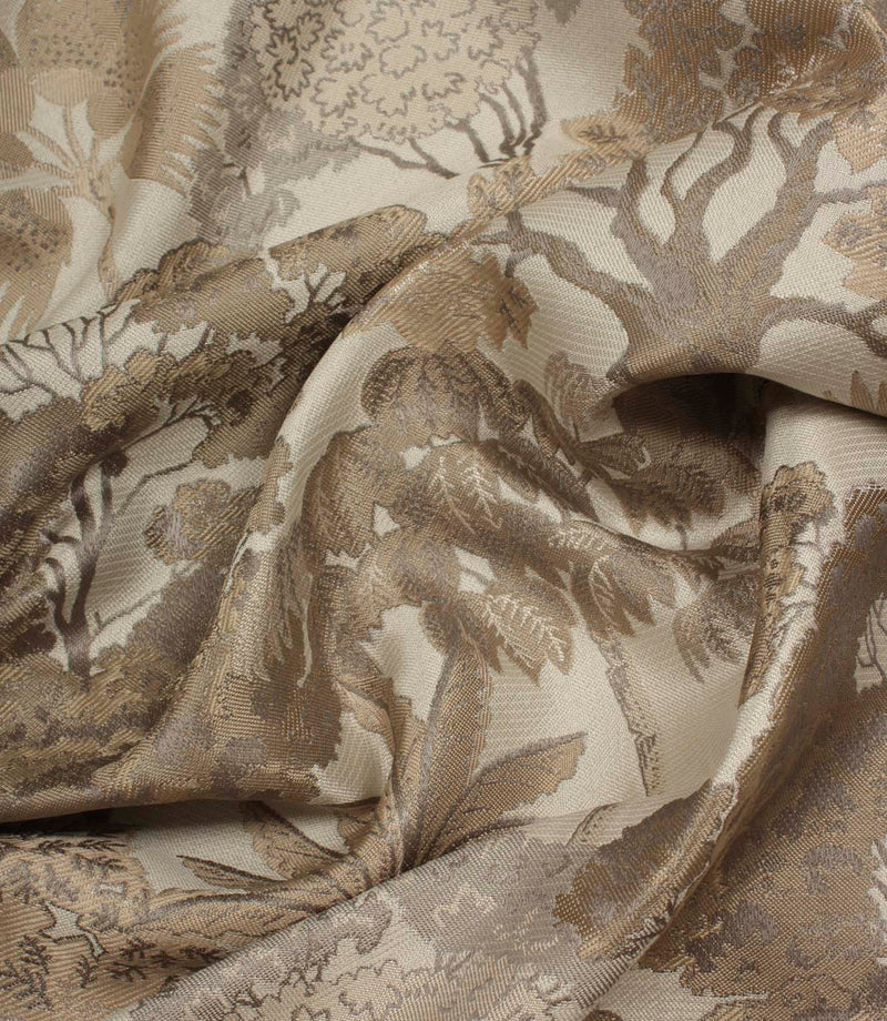 Draped Woodlands Natural fabric emphasising the luxurious handle, soft sheen and intricate woven woodland design in natural shades.
