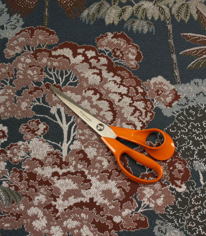 Woodlands Navy furnishing fabric with scissors for scale, showcasing the large-scale forest pattern and woven texture.