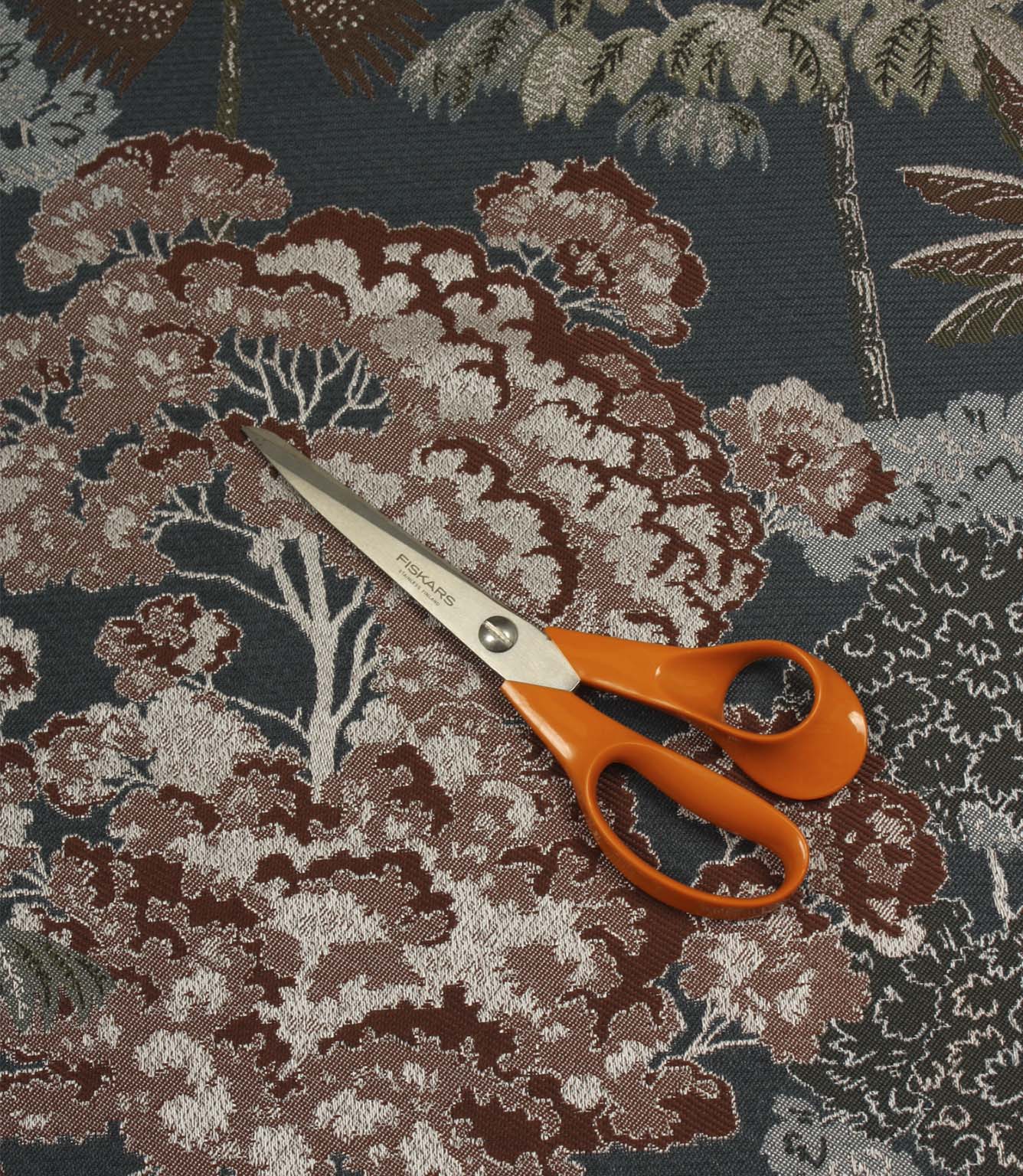 Woodlands Navy furnishing fabric with scissors for scale, showcasing the large-scale forest pattern and woven texture.
