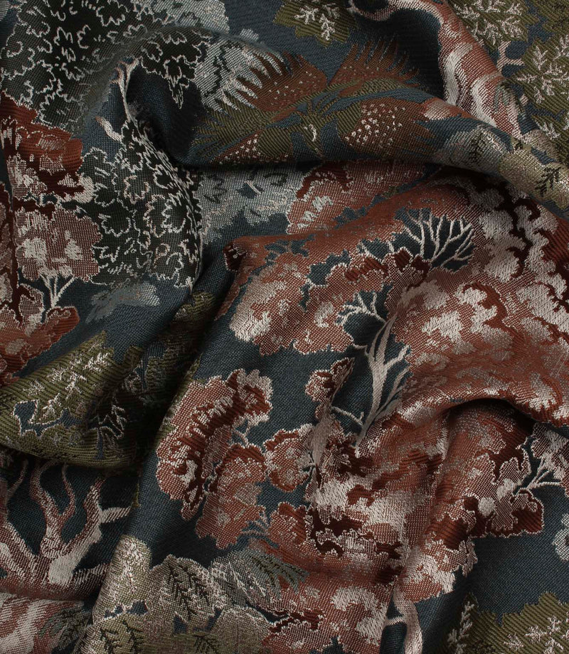 Draped Woodlands Navy fabric emphasising the fluid handle, dimensional weave and elegant forest landscape pattern.