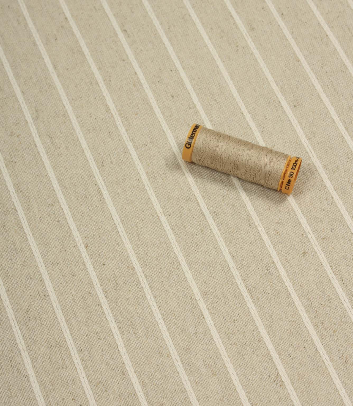 Wooton Wide striped woven fabric displayed with coordinating thread spool, highlighting its soft upholstery texture.
