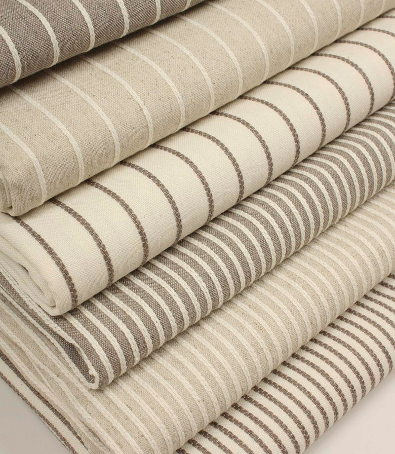 Coordinating striped upholstery fabrics from the Wedmore collection displayed folded together in complementary woven designs.