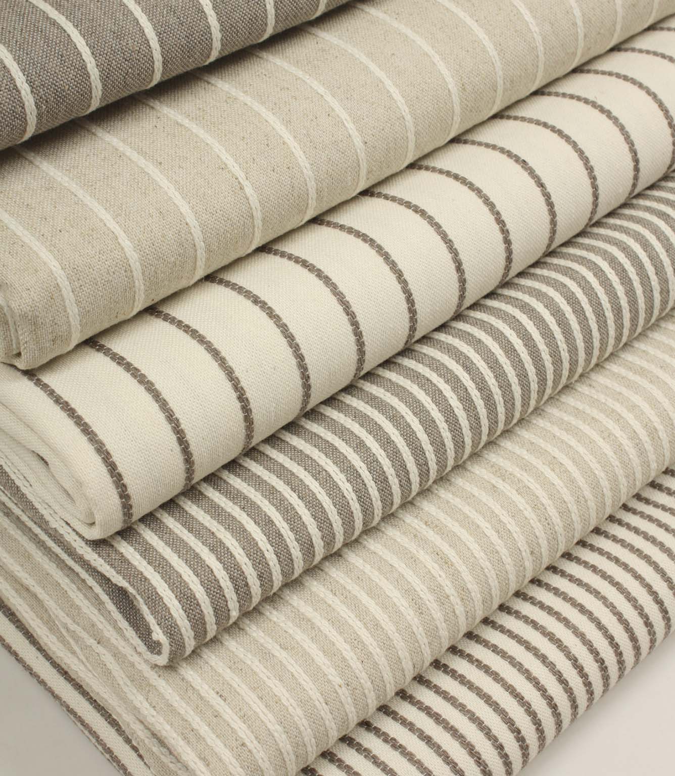 Coordinating striped upholstery fabrics from the Wedmore collection displayed folded together in complementary woven designs.