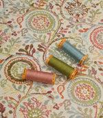 Wychwood Jasmine fabric displayed with coordinating blue, green and blush pink thread spools highlighting the woven floral design.